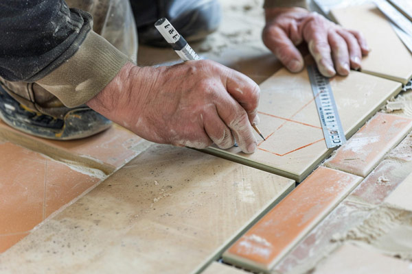 Man installing tiles on a floor, ensuring precision and quality.