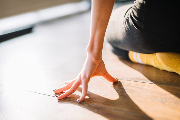 A woman sitting on the floor with her hands on her knees.